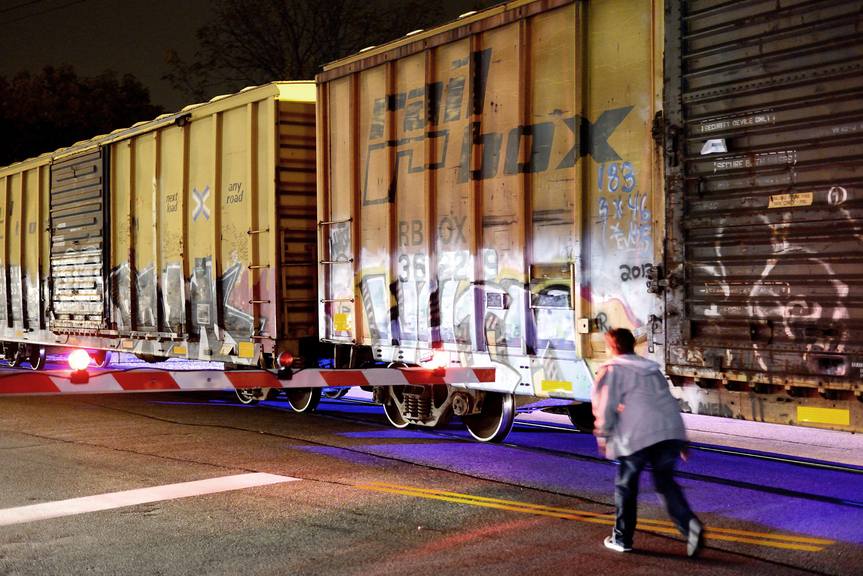 A parked freight train blocks a passing pedestrian following a fata accident along the stretch of train tracks between Forest Avenue and Irving Street in Portland on Wednesday, Oct. 17, 2013. A man who was walking along the tracks was struck and killed by a freight train Wednesday night, police said. When the freight train stopped, it blocked Forest Avenue from 7:15 to about 10 p.m.