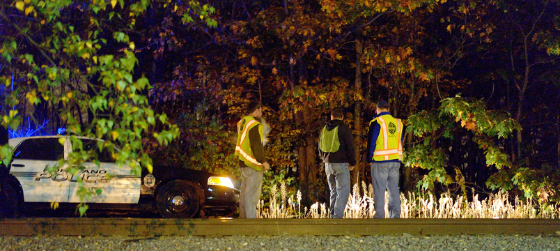 Investigators survey the scene of a fatal accident along the stretch of train tracks between Forest Avenue and Irving Street in Portland on Wednesday. A man who was walking along railroad tracks was struck and killed by a freight train Wednesday night, police said.