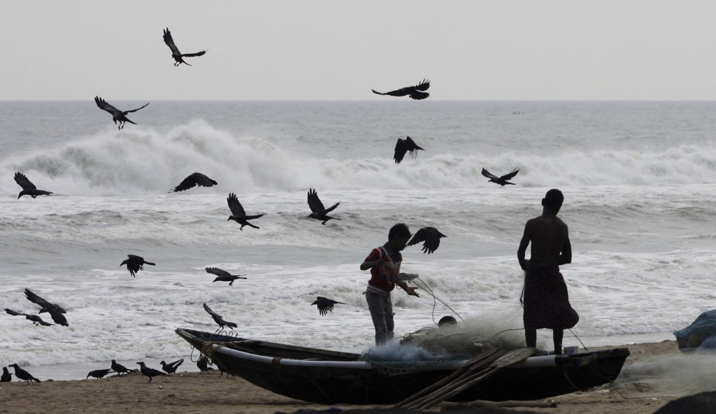 Indian fishermen sort their nets after returning with their catch off the Bay of Bengal. The country is preparing for a cyclone of deadly proportions.
