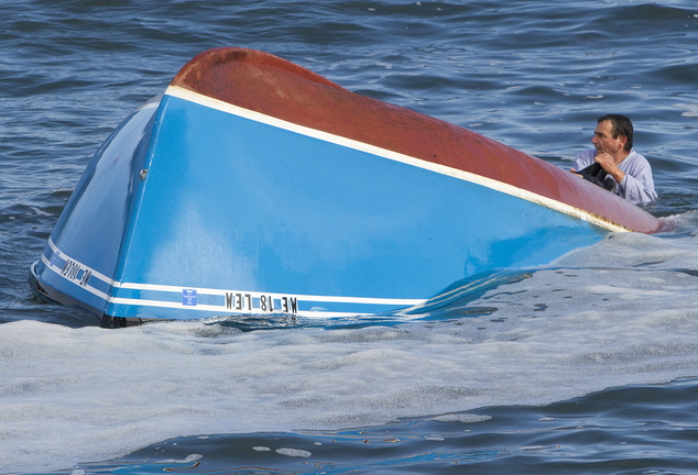 A fisherman from the boat that overturned in rough surf between Wells Beach and Drakes Island holds on to the capsized boat while awaiting rescue Sunday.
