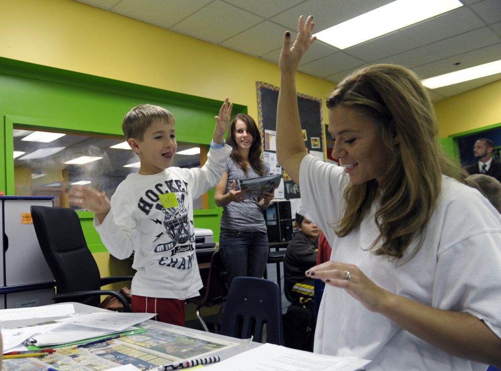 Josh Gillespie, 8, high-fives parent helper Shannon Morgan, right, after they solved a math problem during a lesson at the Andrews Air Force Base, Md., homeschooling cooperative with a math class teacher Jennifer Whittaker, center.