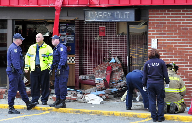 Firefighters, state police and Skowhegan Police Chief Ted Blais, second from left, investigate the scene where a truck loaded with lumber crashed into the Pizza Hut restaurant in Skowhegan on Monday.
