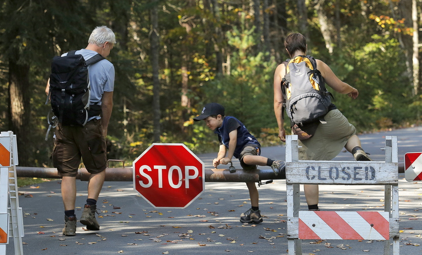 Gabe Souza/Staff Photographer Titus Steinberg, 5, of Herne, Germany, hops over the gate at Acadia National Park's Echo Lake in Southwest Harbor Wednesday, October 2, 2013, along with his parents Oliver, at left, and Ramona, at right. The family was one of a handful of visitors who wouldn't let the closure of Acadia National Park stop them from entering it.