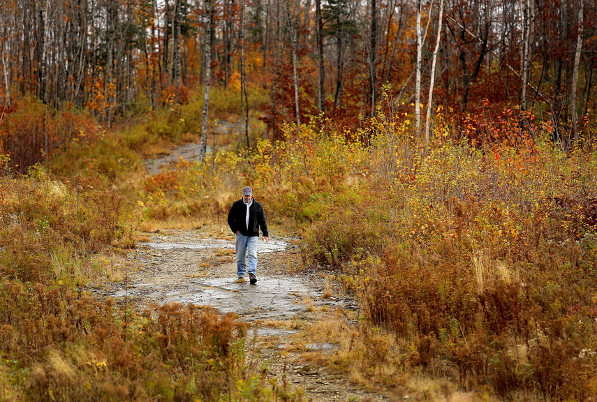 Dave Fowler, New England development director for First Wind, walks along a ridge in the Oakfield Hills this month. Thanks in part to a lucrative community benefits package, Oakfield has embraced plans by the company to build a 50-turbine wind farm scheduled to be online by 2015.
