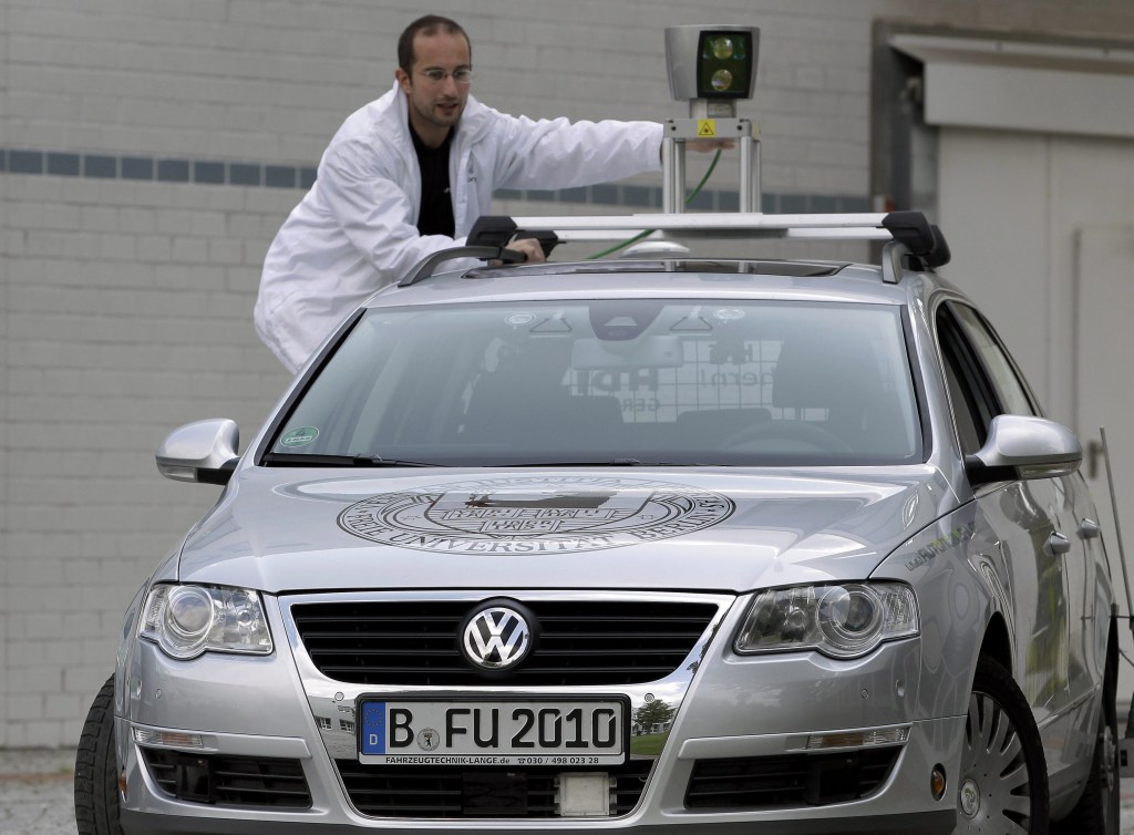 A technician in Germany adjusts a GPS on a Volkswagen capable of driving itself. General Motors, BMW, Toyota, Ford, Audi and others also have begun testing no-driver systems.
