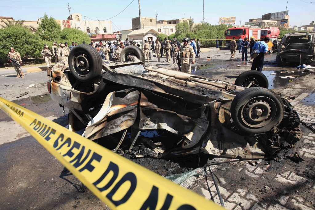 Security forces inspect the site of a car-bomb attack in Basra, 340 miles southeast of Baghdad, Iraq, Sunday. A string of bombings in mostly Shiite-majority cities across Iraq on Sunday killed and wounded dozens of people.
