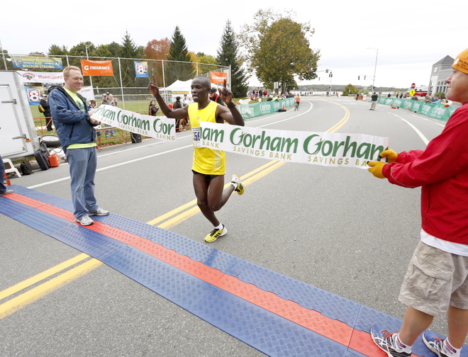 Half-marathon winner Moninda Marube, 34, of Auburn crosses the finish line after winning the Maine half-marathon on Sunday in Portland.