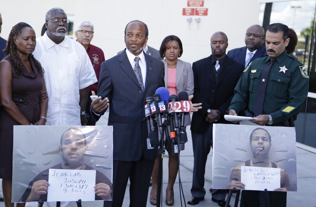 Lillie Danzy, front left, mother of escaped inmate Charles Walker, with her husband Jeff Danzy, second from left, and family supporters and members of the Orange County Sheriff’s Office listen as Henry Pearson, center, uncle of escaped inmate Joseph Jenkins, makes a plea for his nephew to turn himself in to authorities during a news conference in Orlando, Fla., Saturday, Oct. 19, 2013. Joseph Jenkins, photo front left, and Charles Walker, photo front right, two convicted killers freed by bogus paperwork, are at large.