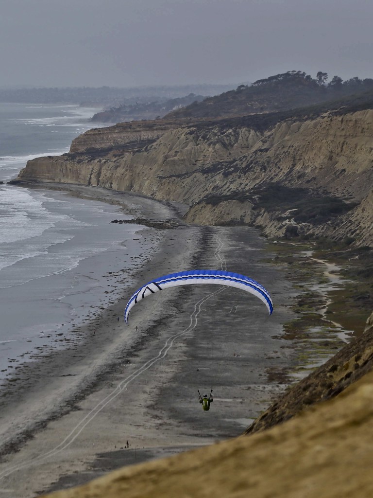 A lone glider sails north over the rugged cliffs of the Southern California coast in San Diego. The glider port is open to the public and offers fantastic views and refreshments.