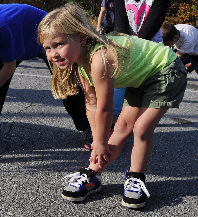 Sebago Elementary School kindergartener Audrey Dubay warms up with other kids before running on Monday.