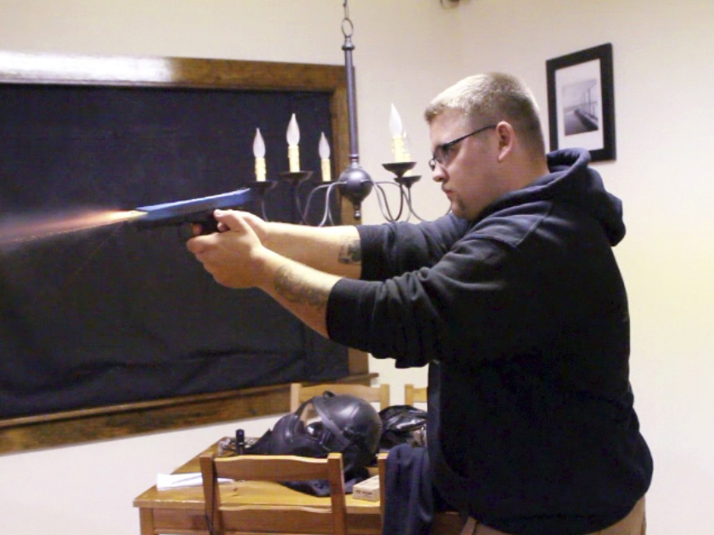Joe Arnson fires a Glock pistol loaded with nonlethal Simunition training ammunition as part of a home invasion training course at Prepare to Act firearm safety training company in Watertown, Conn.