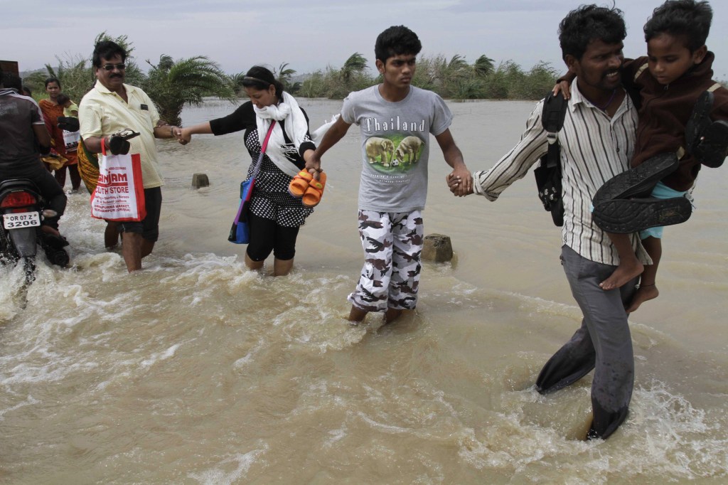 People hold hands as they cross a flooded road to return to their respective villages near Gopalpur, Orissa state, India, on Sunday. Like many others, they survived Cyclone Phailin by heeding evacuation orders.