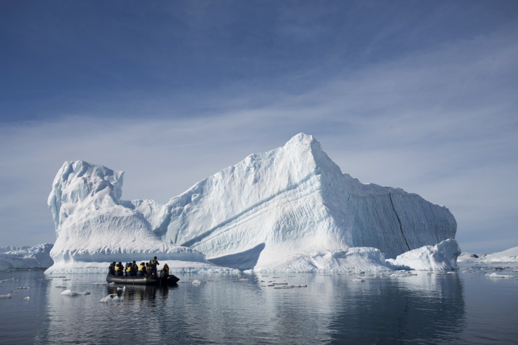 AP An inflatable boat carries tourists past an iceberg along the Antarctic Peninsula.