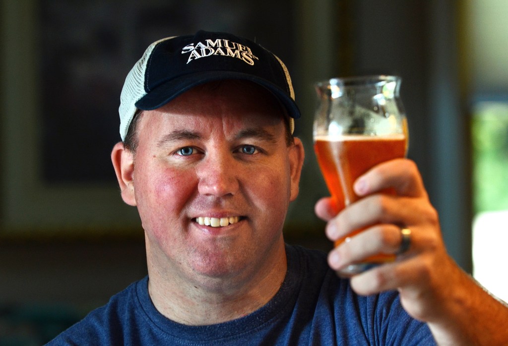 Todd Ruggere toasts his cause at his home in Weymouth, Mass. He says his fundraising method works because “People love beer.” He finds people to be “awesome and generous.”