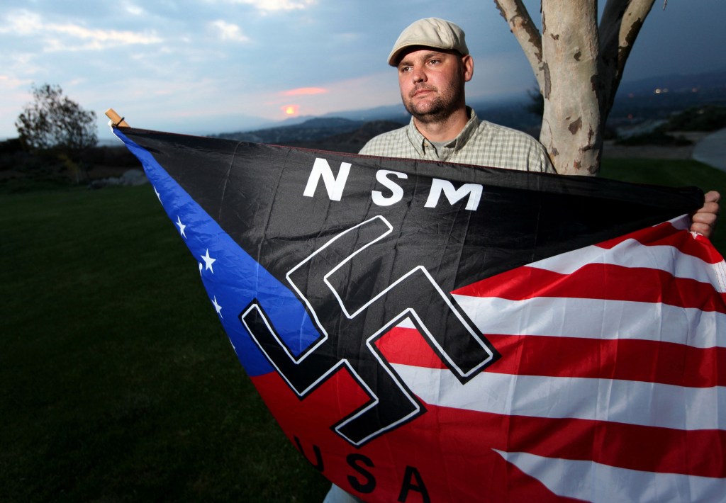 In this Oct. 22, 2010, photo, Jeff Hall, who was killed by his son, holds a neo-Nazi flag while standing in a park near his home in Riverside, Calif.
