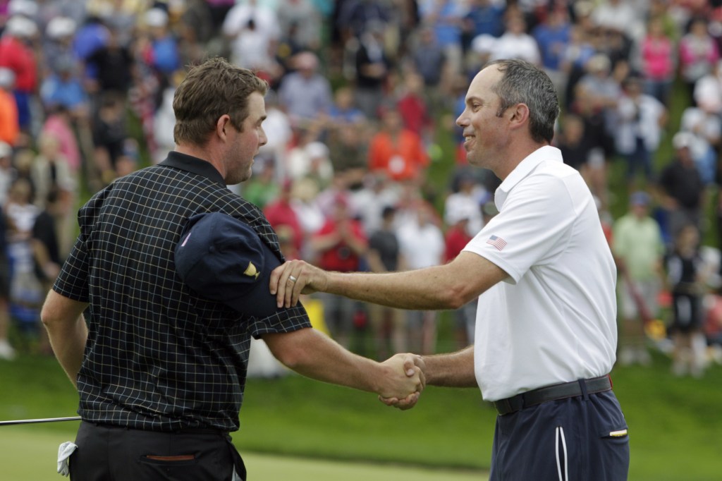 United States team player Matt Kuchar, right, shakes hands with International team player Marc Leishman, of Australia, on the 18th green during the single matches at the Presidents Cup golf tournament at Muirfield Village Golf Club Sunday, Oct. 6, 2013, in Dublin, Ohio.