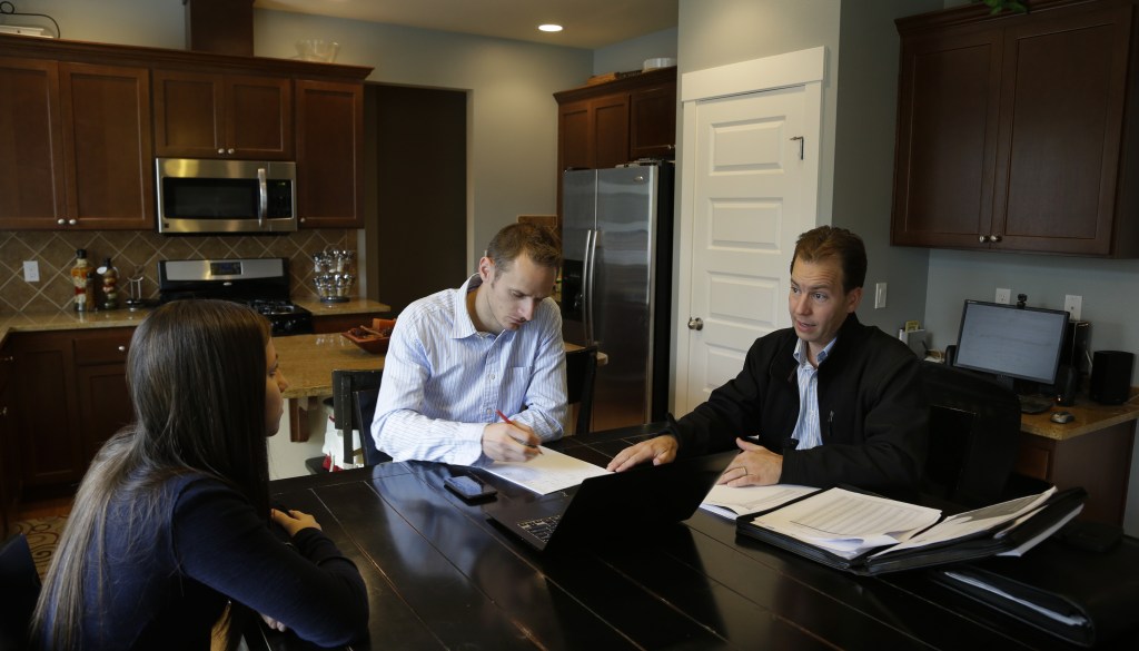 Insurance broker Jeff Lindstrom, right, meets with Brandi and Darren Litchfield to discuss health insurance plan options, at their home in the Seattle suburb of Bothell, Wash. Darren works for a startup company that doesn't yet offer an employee insurance plan, so they invited Lindstrom to outline the options of different healthcare plans that he offers as a broker.