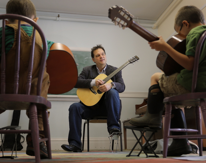 Don Pride teaches a guitar to Oliver Newton, 5, left, and Michael Madden, also 5, in a class for home-schooled students at the Portland Conservatory of Music on Tuesday.