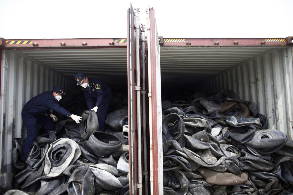 Chinese customs officials check a container of illegally imported used tires in Shanghai.