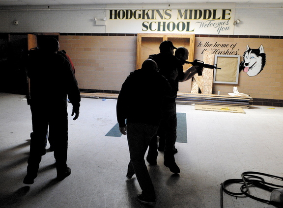 Augusta emergency responders stay low as they follow Augusta police officers into a simulated school shooting incident during a training exercise Thursday at the former Hodgkins Middle School in Augusta.