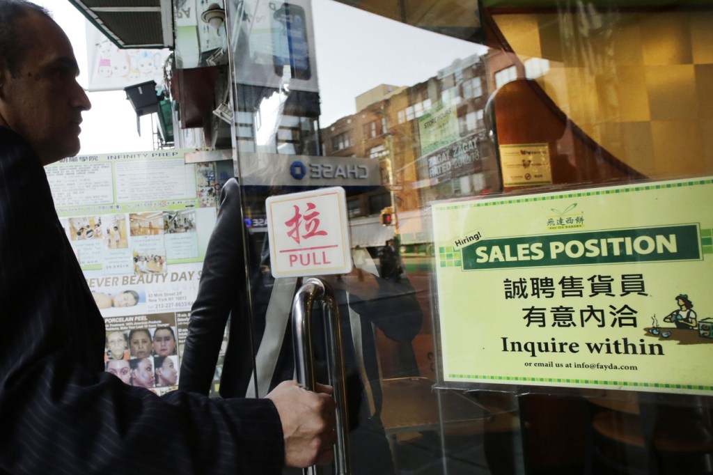 A customer enters a Chinese bakery that has a sign posted in the door, “Hiring! Sales Position Inquire within,” Tuesday in New York. The U.S. economy added just 148,000 jobs in September, suggesting that employers held back on hiring before a 16-day partial government shutdown began Oct. 1. Still, hiring last month was enough to lower the unemployment rate.