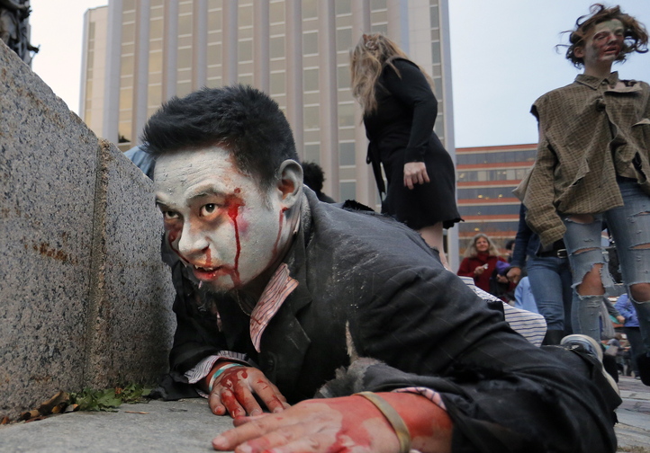 Brian Noyes of Portland, dressed as a vampire zombie, crawls along the base of the monument in Monument Square on Wednesday. Noyes was part of a flash mob performance that attracted about 300 spectators.