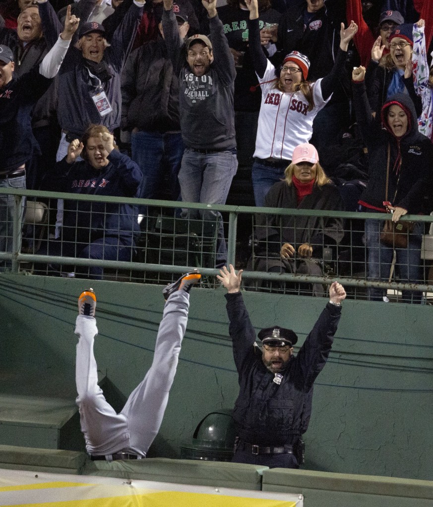 Boston police officer Steve Horgan celebrates as Tigers right fielder Torii Hunter flips over the fence into the bullpen while trying to catch David Ortiz’s grand slam Sunday night.