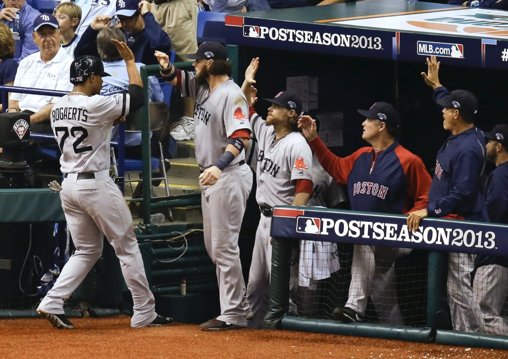 Boston Red Sox’s Xander Bogaerts trades high-fives with teammates in the dugout after he scored in the seventh inning on a wild pitch by Tampa Bay Rays relief pitcher Joel Peralta.