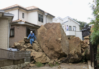 A fire fighter walks over rocks fallen from a cliff over a garage and a road in a residential area in Kamakura, southwest of Tokyo, after a powerful typhoon hit Japan’s metropolitan area Wednesday morning, Oct. 16, 2013. Typhoon Wipha triggered landslides and caused multiple deaths on a Japanese island off Tokyo, before sweeping up the country’s east coast, grounding hundreds of flights and paralyzing public transportation in Tokyo during Wednesday morning’s rush hour.