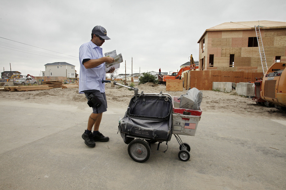 A postal worker makes his rounds through Breezy Point in the Queens borough of New York on Oct. 17. A year ago on Oct. 29 flooding and a fire swept through the neighborhood, leveling more than 100 homes. The house on the right is one of the few homes that burned to the ground that is now under reconstruction.