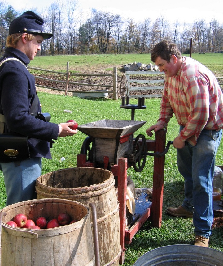 A visitor tries his hand at making cider as a period re-enactor looks on at the Washburn-Norlands Living History Center in Livermore. The center invites the public to step back in time at its fall festival on Saturday to see how it interprets farming in the 1870s, while raising funds for the rebuilding of its historic barn, destroyed by fire in 2008.