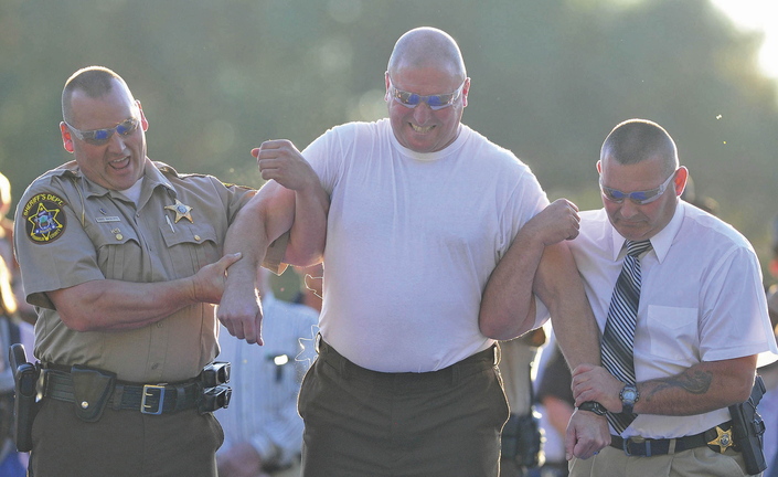 Franklin County Sheriff Scott Nichols, center, is supported by Lt. David Rackliffe, left, and Lt. David St. Laurent, right, after being stunned with a Taser gun by Chief Deputy Steven Lowell, back, during the department’s open house Wednesday in Farmington.