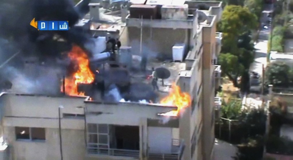 In this image taken from video obtained from the Shaam News Network, which has been authenticated based on its contents and other AP reporting, people try to extinguish a fire on the roof of a building, allegedly caused by shelling in Homs, Syria, on Thursday. President Bashar Assad’s government met a key deadline in an ambitious plan to eliminate Syria’s entire chemical weapons stockpile by mid-2014 and avoid international military action.