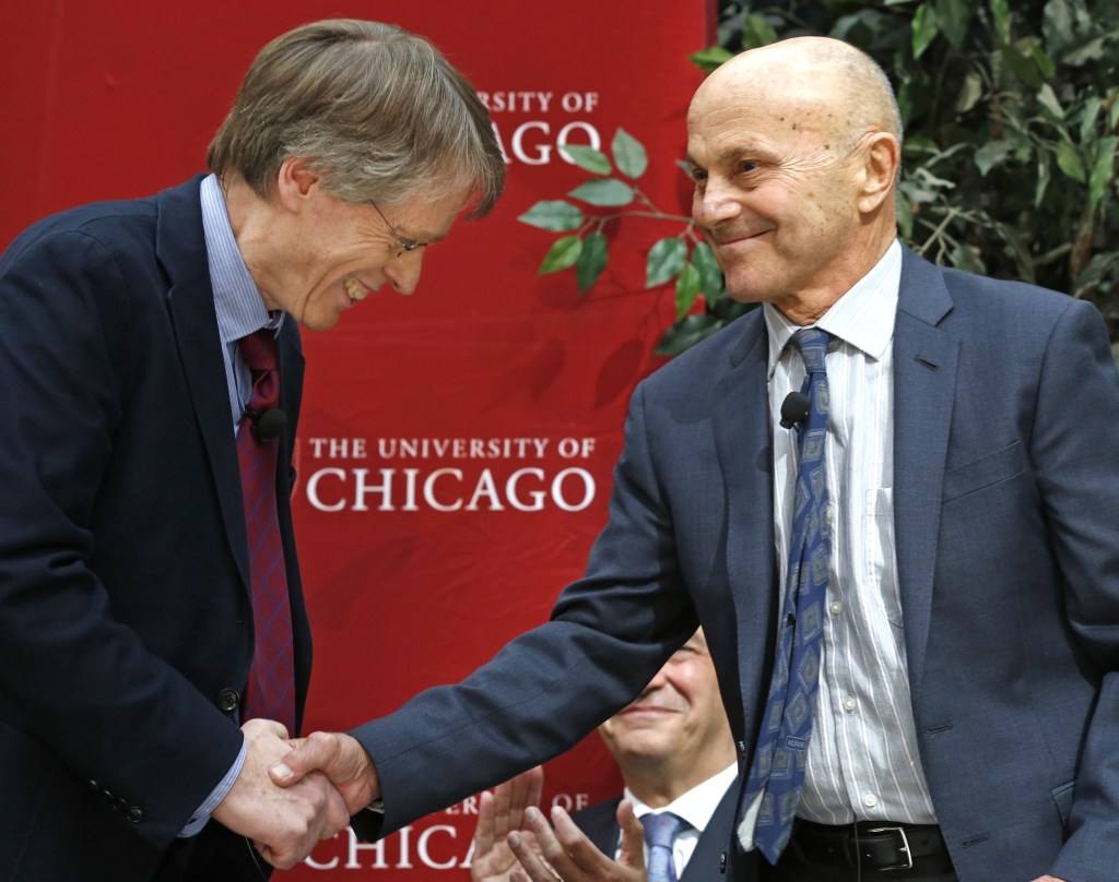 Nobel Prize winners Lars Peter Hansen, 60, left, and Eugene Fama, 74, of the University of Chicago, shake hands at a news conference Monday, Oct. 14, 2013, in Chicago after being named two of the three winners of the Nobel prize for economics. They share the prize with Robert Shiller, 67, of Yale University.