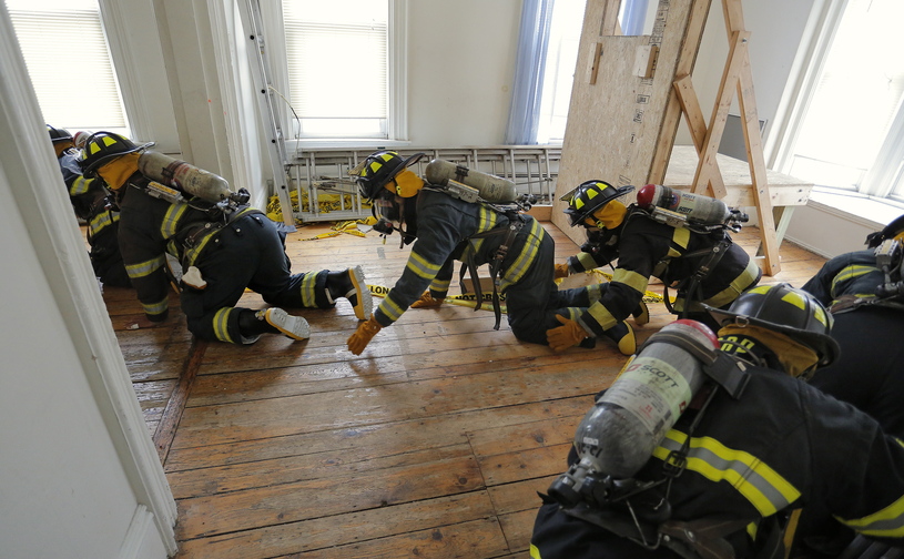 Students from Portland and Deering high schools work their way through a vacant building at 65 Elm St. in Portland on Saturday as part of their yearlong Introduction and Orientation to Fire Service course.