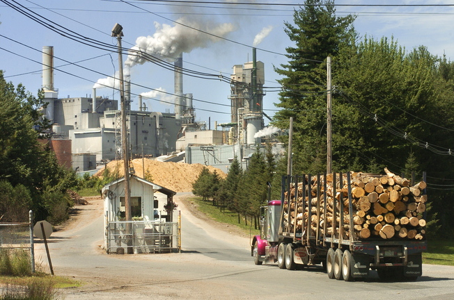 A truck loaded with logs enters a paper mill in Jay in 2005. The paper industry backs Maine’s proposal to ease anti-smog rules, saying it will remove a barrier to major investments in mills. Wood pellet manufacturers also have expressed support.