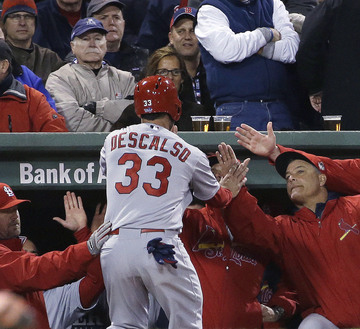 Daniel Descalso of the Cardinals is congratulated at the dugout after scoring on Carlos Beltran’s single, the final run of a three-run seventh inning Thursday night that gave St. Louis a 4-2 victory and a 1-1 tie in the World Series. The series will resume Saturday night in St. Louis.
