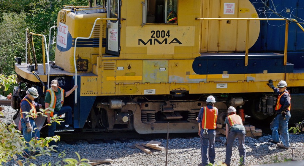 A crew from Montreal, Maine & Atlantic Railway works to put a derailed locomotive back on the tracks in Brownville in July. A creditor has sued the railroad over its $6 million debt.