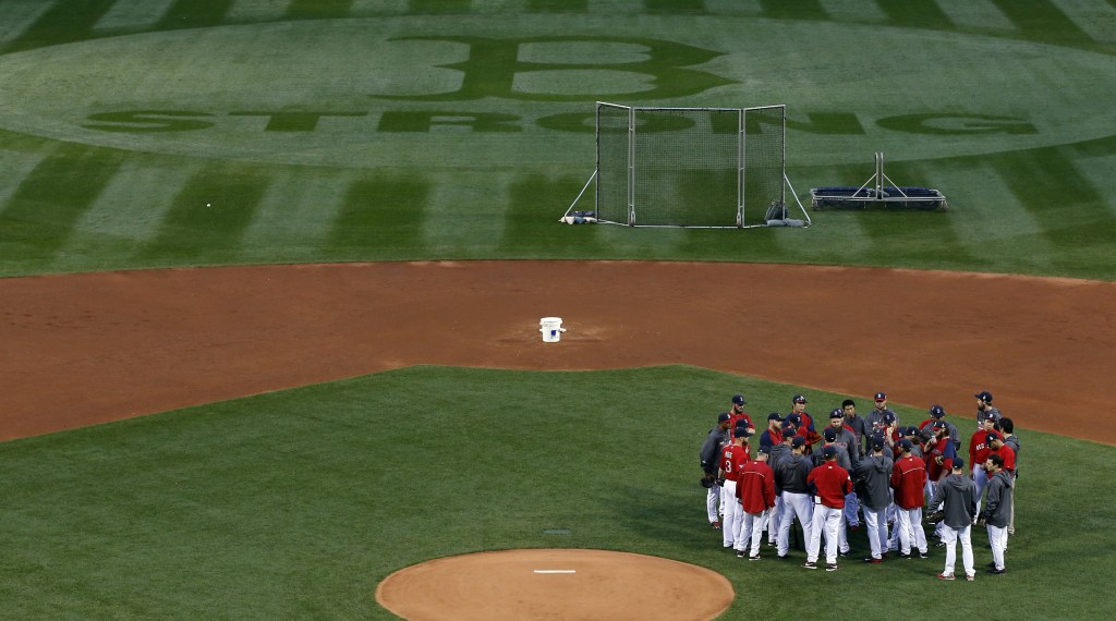 Boston Red Sox players and coaches gather in the infield before a workout at Fenway Park Tuesday.