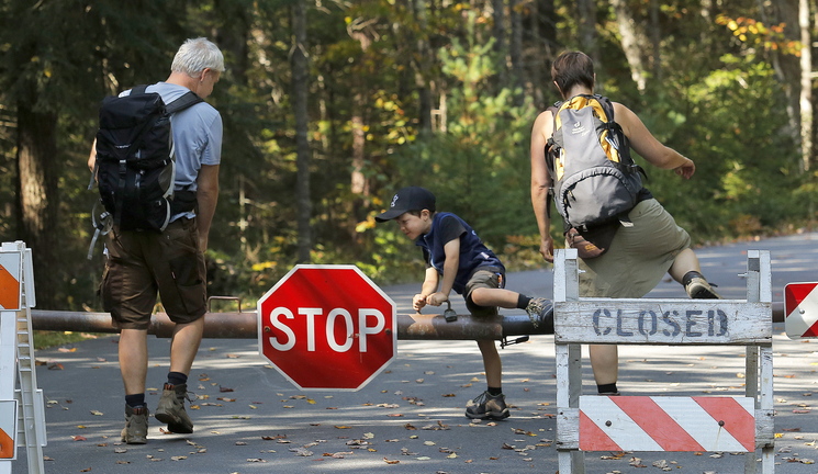 Despite the closed sign, Titus Steinberg, 5, of Herne, Germany, hops over the gate at Acadia National Park’s Echo Lake in Southwest Harbor on Wednesday, along with his parents Oliver, at left, and Ramona.