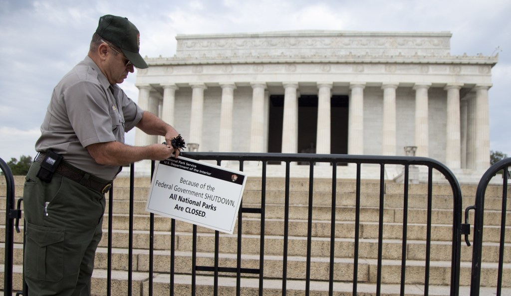 A National Park Service employee posts a sign on a barricade to close access to the Lincoln Memorial in Washington on Tuesday. Congress plunged the nation into a partial government shutdown Tuesday as a long-running dispute over President Barack Obama’s health care law stalled a temporary funding bill, forcing about 800,000 federal workers off the job and suspending most non-essential federal programs and services.