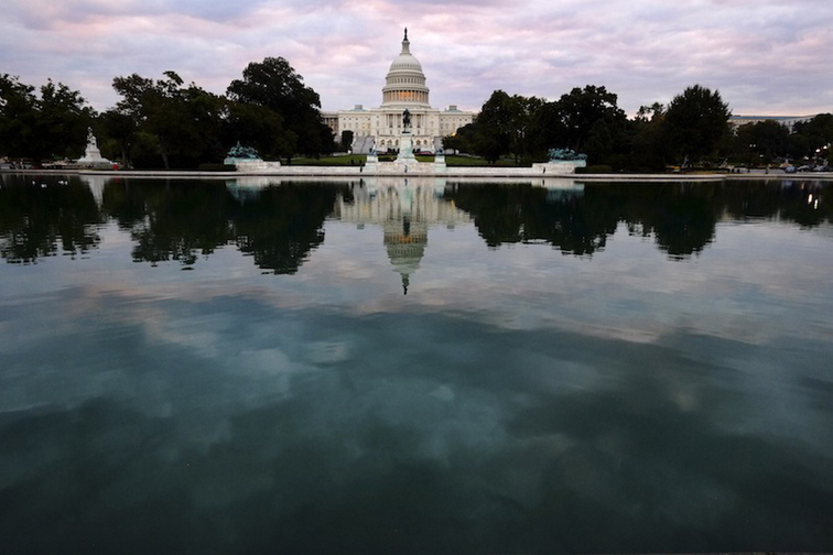 The Capital is mirrored in the Capital Reflecting Pool on Capitol Hill in Washington early Tuesday, Oct. 1, 2013. Congress plunged the nation into a partial government shutdown Tuesday as a long-running dispute over President Barack Obama’s health care law stalled a temporary funding bill, forcing about 800,000 federal workers off the job and suspending most non-essential federal programs and services.