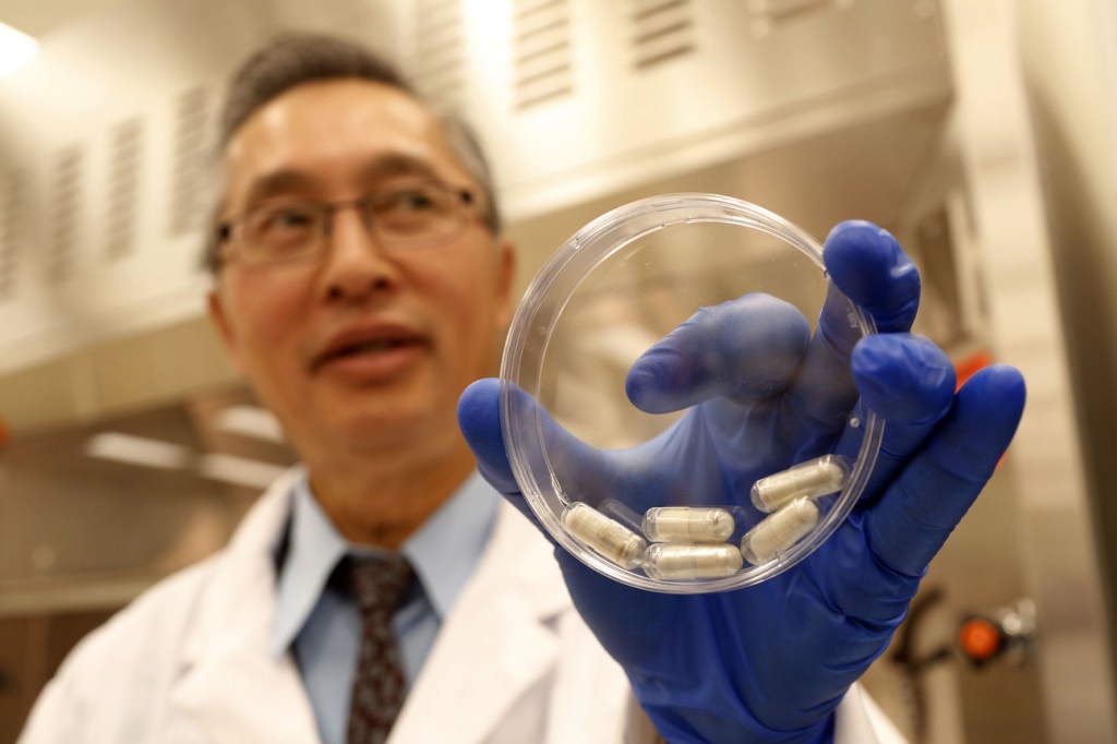 Dr. Thomas Louie, an infectious disease specialist at the University of Calgary, holds a container of stool pills in triple-coated gel capsules in his lab in Calgary, Alberta, Canada, last month.