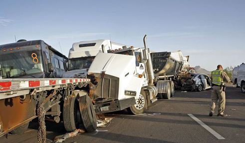 Public safety officers investigate a 19-vehicle pileup caused by a dust storm Tuesday on Interstate 10 south of Casa Grande, Ariz. Three people were killed and 12 wee injured.