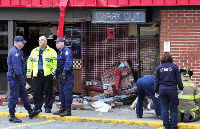 Firefighters, state police and Skowhegan Police Chief Ted Blais, second from left, investigate the scene where a truck loaded with logs crashed into the Pizza Hut restaurant in Skowhegan, killing driver Michael Morin of Oakland.