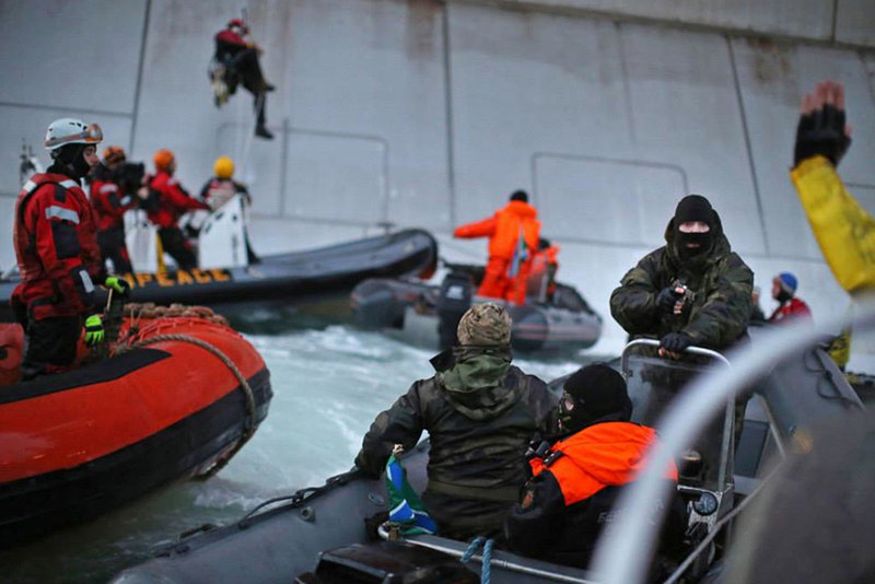 A Russian Coast guard officer is seen pointing a gun at a Greenpeace International activist as five activists attempt to climb the 'Prirazlomnaya,' an oil platform operated by Russian state-owned energy giant Gazprom platform in Russia's Pechora Sea. The activists were there to stop it from becoming the first to produce oil from the ice-filled waters of the Arctic.