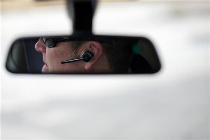 In this December 2011 file photo, Dan Johnson uses a hands-free device to talk on a cellphone while driving. Maine law enforcement officers will have to get search warrants to gather information from cellphones including voicemails, text messages or location data, under two laws that will take effect Wednesday.