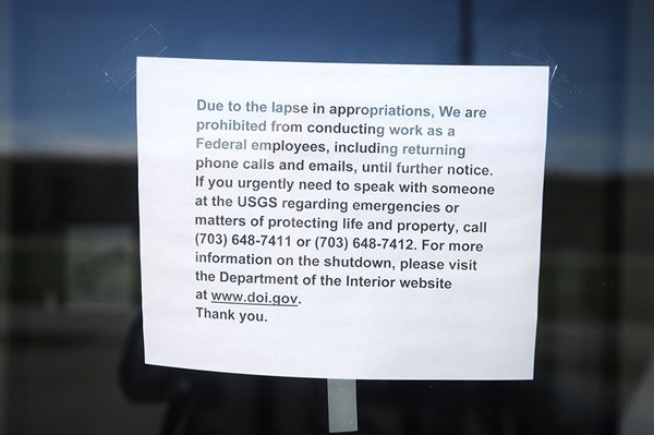 A paper sign describing the government shutdown hangs on the entrance of the U.S. Geological Service building on Whitten Road in Hallowell, Maine.