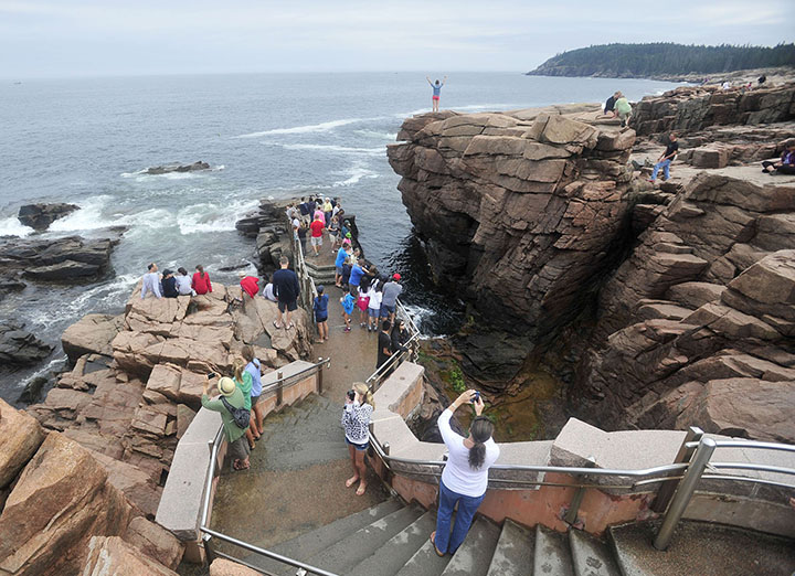Crowds of people gather around Thunder Hole at Acadia National Park in Bar Harbor in July. As congressional leaders raced to seal a deal that would reopen the government, lawmakers from both parties jabbed at one another Wednesday over who was to blame for the most high-profile casualties of the 16-day shutdown: the national parks.