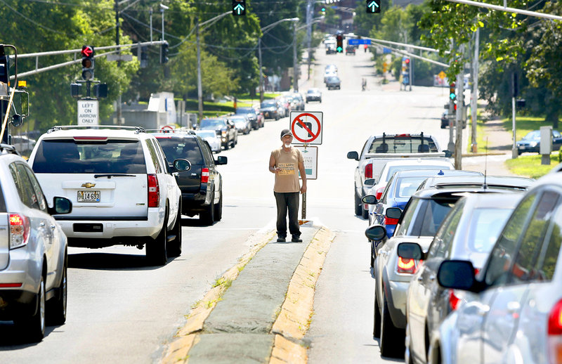 In this July 16, 2013 file photo, a man panhandles on a median on the corner of Marginal Way and Forest Avenue in Portland. Portland officers are using criminal trespass notices – and the threat of jail time – to keep chronic panhandlers off the medians.